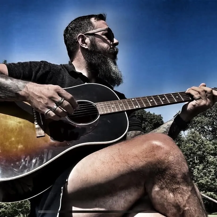 Will Cybertron playing an acoustic guitar outdoors