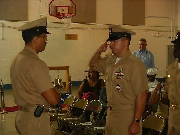 Will Cybertron in Navy khakis and a chief petty officer cover, saluting at a ceremony